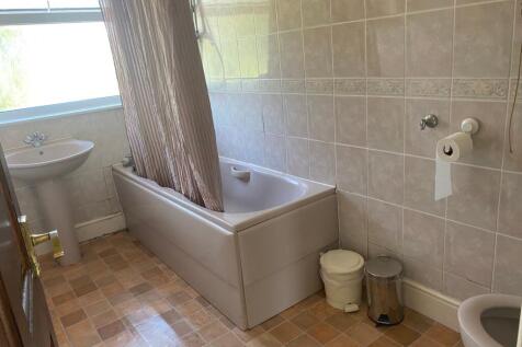 A clean and spacious bathroom featuring a bath ...