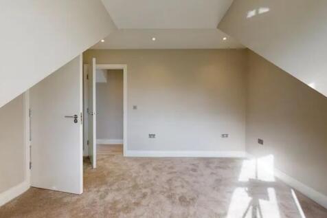 Bright attic room with beige walls and carpet f...