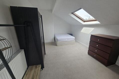 A cozy bedroom with a sloped ceiling and a skyl...