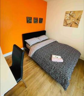 Cozy double bedroom featuring a vibrant orange ...
