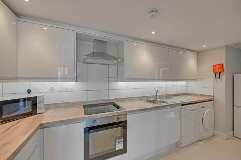 Modern kitchen featuring sleek white cabinetry,...