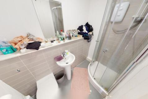 A compact bathroom featuring a modern shower an...