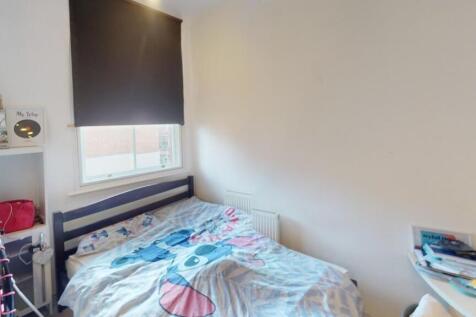 A cozy single bedroom featuring a neatly made b...
