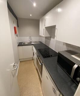 A compact and modern kitchen featuring white ca...