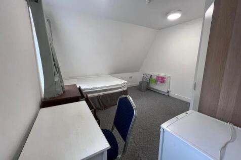Cozy single bedroom featuring a neat desk and c...