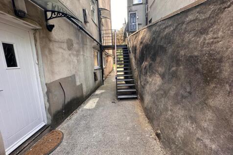 Narrow exterior alleyway beside a building with...