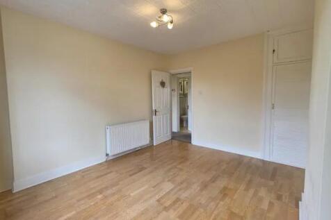 Bright and spacious bedroom with warm wooden fl...