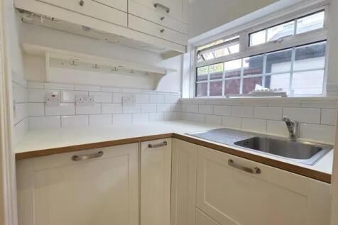 Bright and clean compact kitchen with white cab...