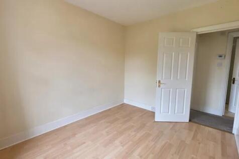 A bright, clean single bedroom with light woode...
