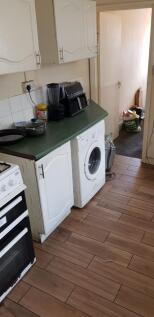 A compact kitchen featuring white cabinetry and...