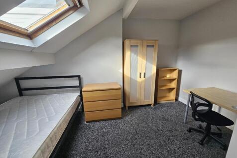 A well-lit single bedroom featuring a bed, a wo...