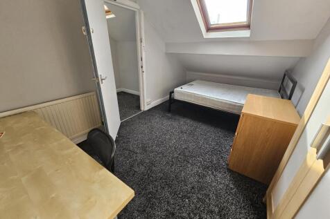 A compact single bedroom featuring a simple bed...