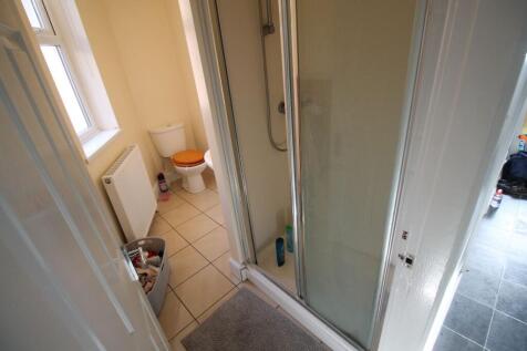 A well-lit bathroom featuring a spacious shower...