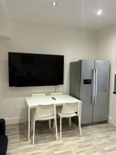 A modern kitchen area featuring a large flat-sc...