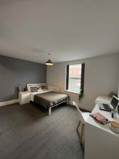 A spacious and bright bedroom featuring a comfo...