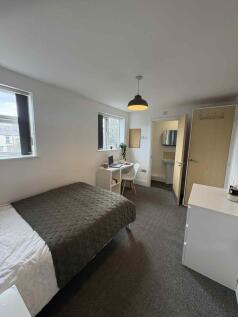 A tidy and well-lit student bedroom featuring a...