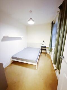 Bright, simply furnished bedroom with a double ...