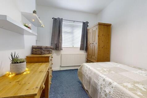 A cozy single bedroom featuring a neatly made b...