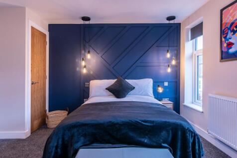 A stylish, well-lit bedroom featuring a spaciou...
