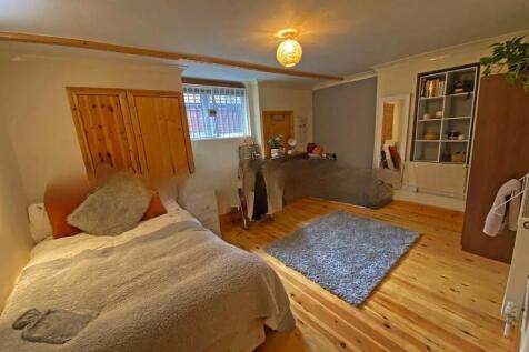 A cozy single bedroom featuring warm wood floor...