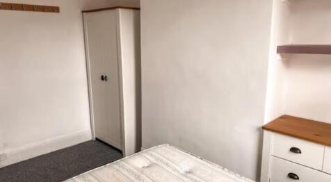A cozy single bedroom featuring a wardrobe, che...