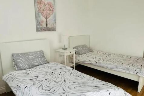 A clean and cozy double bedroom featuring two s...