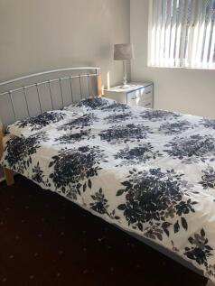 Bright double bedroom featuring a neatly made b...