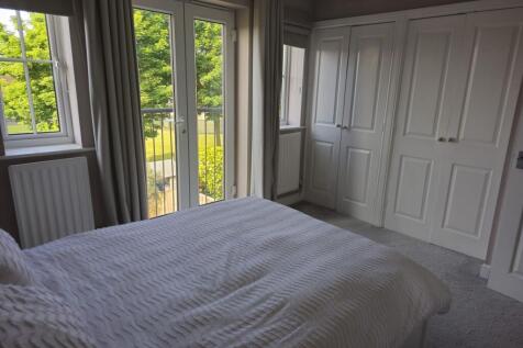 A bright double bedroom featuring large French ...