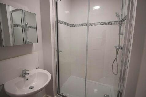 A modern bathroom suite featuring a glass-enclo...