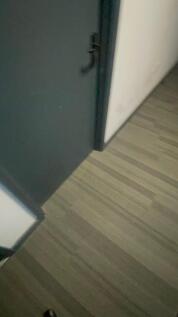 A simple hallway featuring a dark-colored door ...