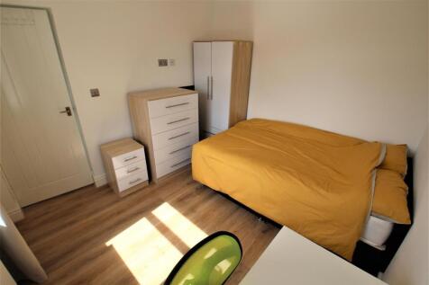 A bright, tidy single bedroom featuring warm wo...