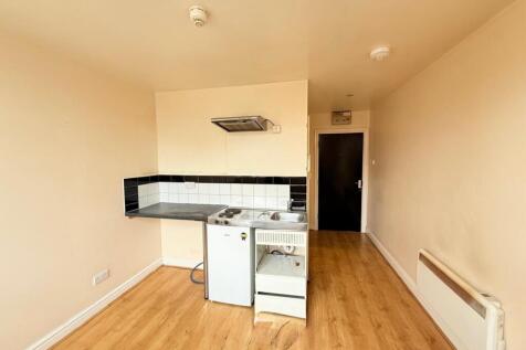 Compact kitchen area featuring a small fridge, ...