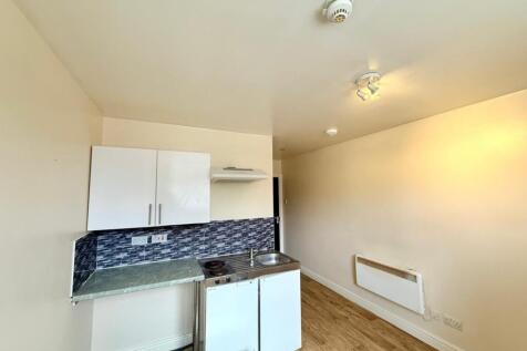 Compact kitchen area featuring white cabinetry,...