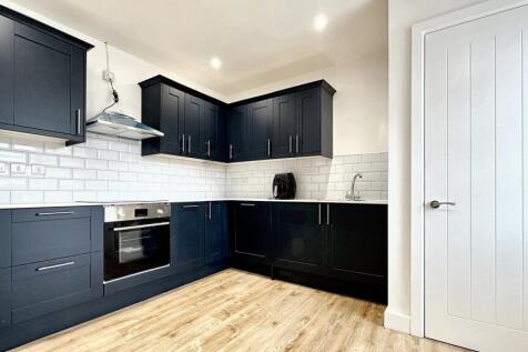 A modern kitchen featuring sleek dark cabinetry...