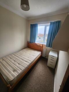 Cozy single bedroom featuring a wooden bed fram...