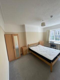 A bright double bedroom featuring a wooden bed ...
