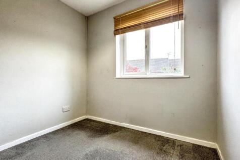 A small, neutral-colored room with a single win...