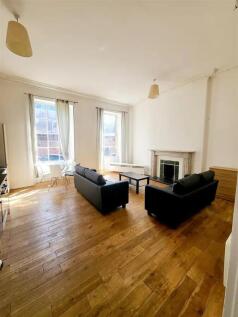 A spacious, bright living room with large windo...