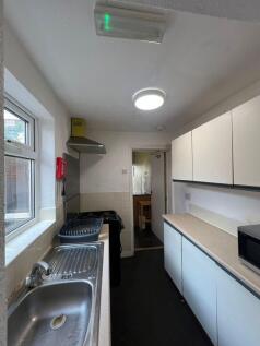 A narrow kitchen featuring a stainless steel si...