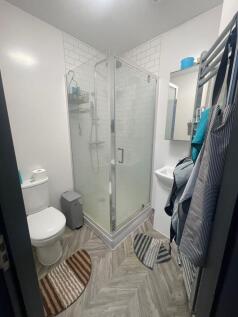 A modern and tidy bathroom featuring a glass-en...