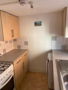 Compact kitchen featuring light wood cabinetry,...