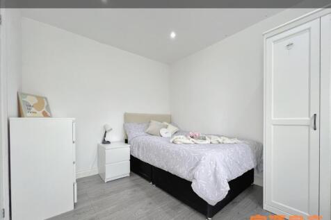A neat and tidy single bedroom featuring a cozy...