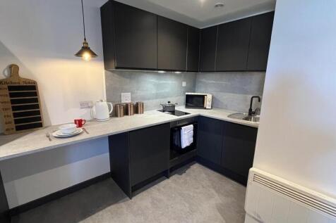 A modern compact kitchen featuring sleek black ...