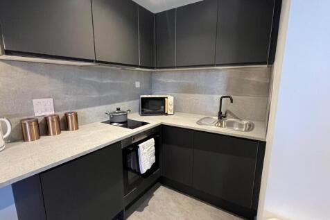 A sleek modern kitchen with dark matte cabinets...