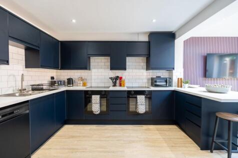 Modern kitchen featuring sleek dark cabinetry w...