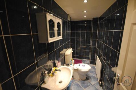 A modern bathroom suite featuring dark tiled wa...