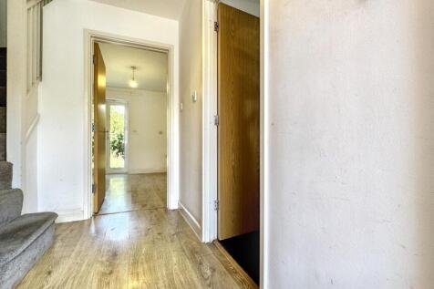 Bright and clean hallway with wooden flooring a...