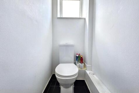A clean and bright single toilet with white wal...