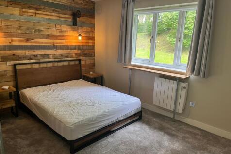 A cozy double bedroom featuring a stylish wood-...