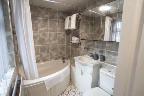 A modern bathroom suite featuring a corner bath...